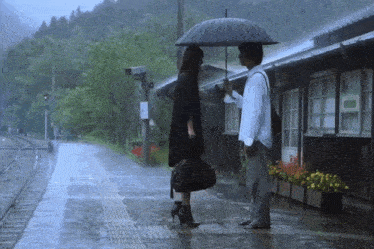 a man holding an umbrella stands next to a woman in the rain