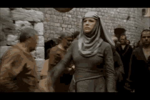 a woman in a hijab is walking through a crowd of people .