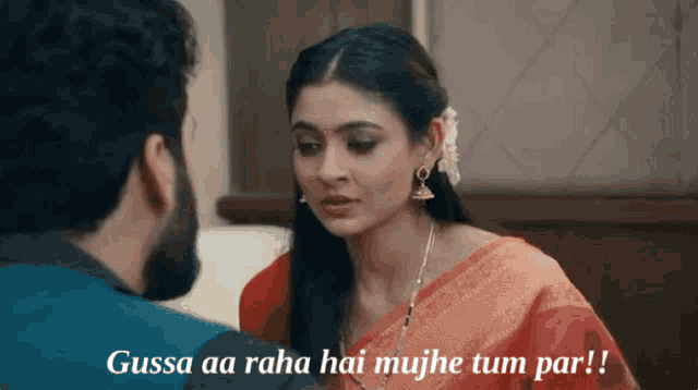 a man and a woman are looking at each other and the woman is wearing a red saree