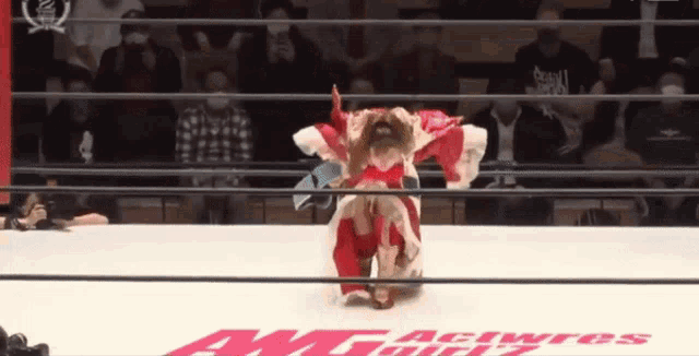 a woman in a red kimono is wrestling in a ring that says awt