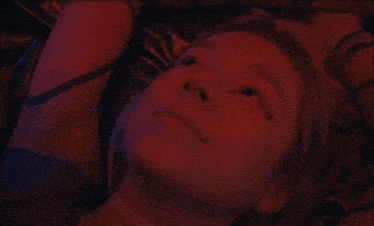 a close up of a woman 's face with red light behind her