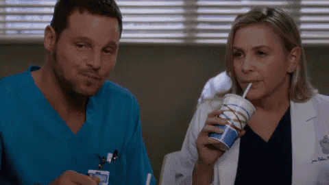 a man and a woman are sitting next to each other drinking from a cup .