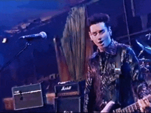 a man playing a guitar on a stage with a marshall amplifier in the background