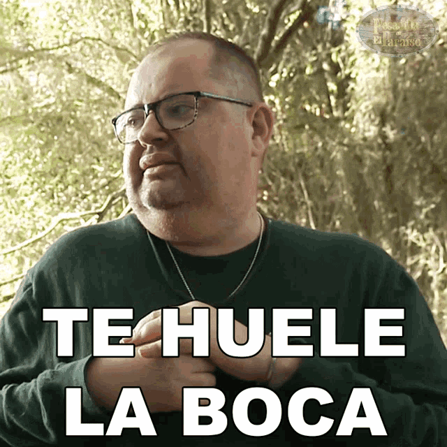 a man wearing glasses and a green shirt has the words te huele la boca on his chest