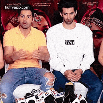 two men are sitting next to each other with one wearing a shirt that says one on it