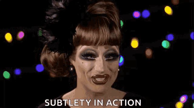 a drag queen is making a funny face and the words subtlety in action are on the screen .