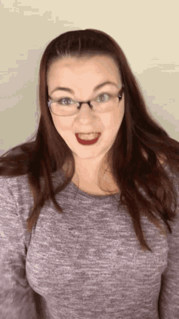 a woman wearing glasses and a purple shirt is smiling