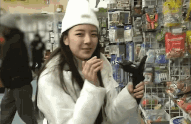 a woman wearing a white hat and a white jacket is holding a black object .
