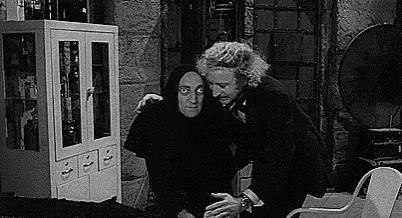 a black and white photo of a man hugging another man .