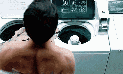 a shirtless man is standing in front of a washing machine with instructions on how to use the machine