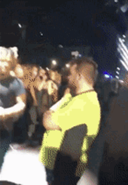 a blurry picture of a crowd of people including a man in a yellow shirt