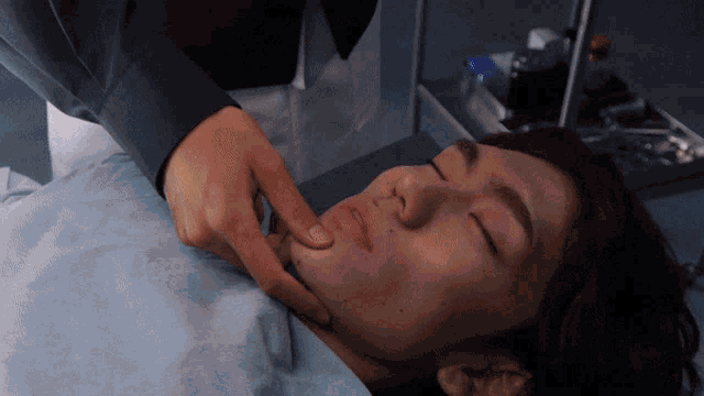 a person is touching another person 's face in a hospital room