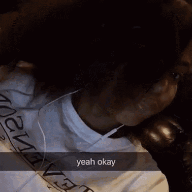 a woman is laying on a couch wearing headphones and a snapchat that says yeah okay