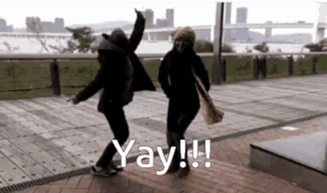 a man and a woman are dancing on a sidewalk with the words yay !! written on the bottom .