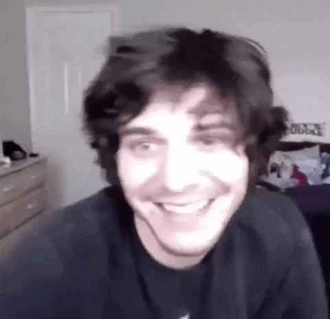 a close up of a man 's face smiling in a bedroom .
