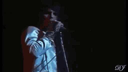 a man in a white shirt is singing into a microphone .