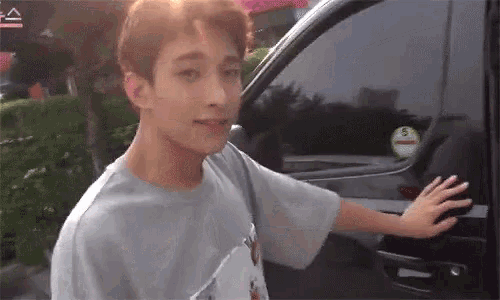 a young man standing next to a car with a sticker on the window that says ' a ' on it
