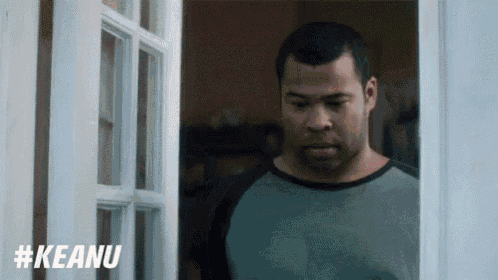 a man is standing in front of a door with the word keanu written on it .