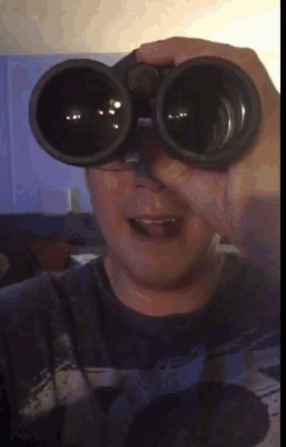 a man is looking through binoculars with a surprised look on his face