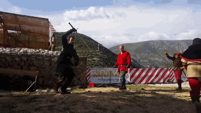 a man holding a sword stands in front of a sign that says ' slackman ' on it