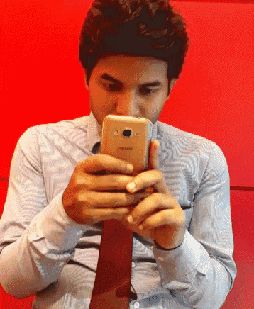 a man in a striped shirt and tie is using a samsung cell phone
