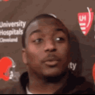 a close up of a man 's face with a university hospitals logo in the background .
