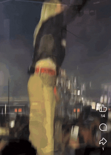 a blurry picture of a person standing on a stage with a thumbs up and a thumbs down