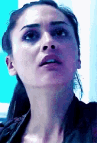 a close up of a woman 's face with a ponytail and a blue background .