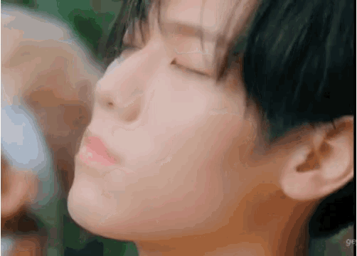a close up of a person 's face with their eyes closed and a blurry background .