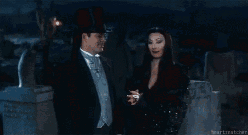 a man and a woman are standing next to each other in a cemetery at night .