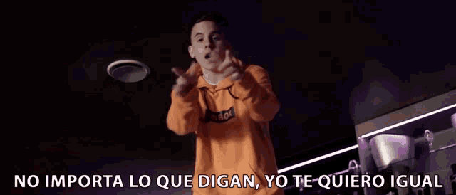 a man in an orange hoodie is giving a thumbs up