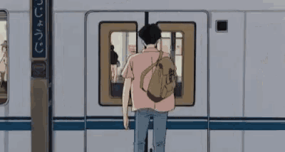 a man with a backpack is standing in front of a subway car .