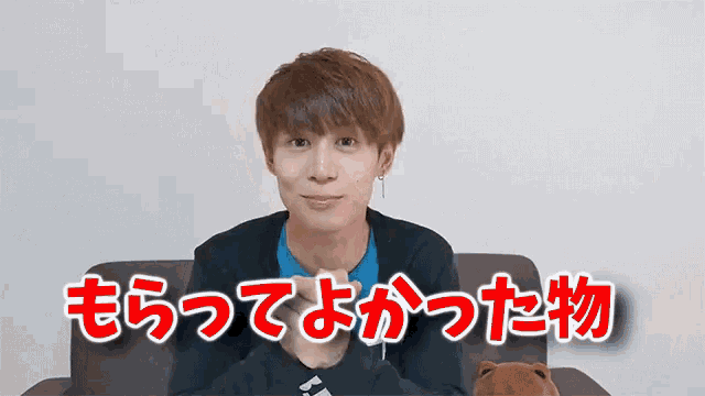 a young man is sitting on a couch with a teddy bear in front of him with chinese writing on the couch