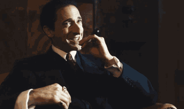 a man in a suit and tie is smiling while holding a cell phone