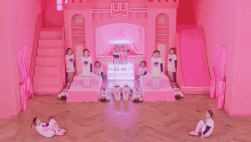a group of children are dancing in a pink room with a pink castle in the background .