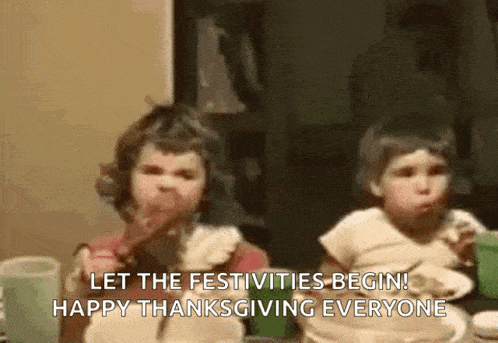 two little girls are sitting at a table eating food and saying let the festivities begin happy thanksgiving everyone .