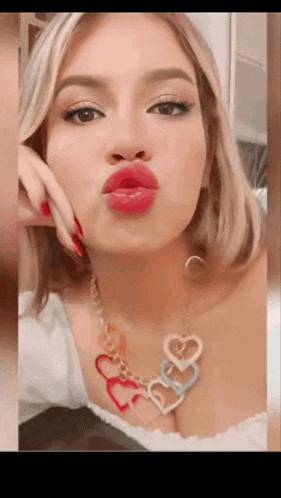 a woman wearing a necklace with hearts on it is making a funny face .