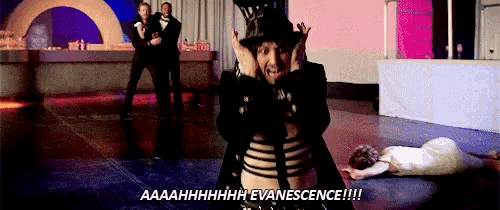 a man in a top hat is screaming while a woman in a white dress is laying on the floor ..