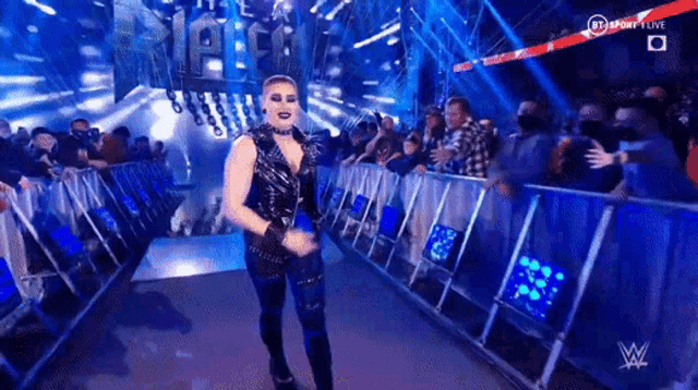 a woman in a black outfit is walking down a ramp in front of a crowd of people .