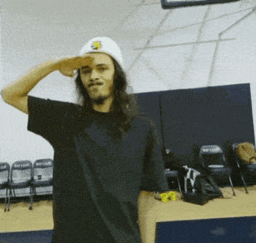 a man wearing a white hat salutes in front of a row of bay club chairs
