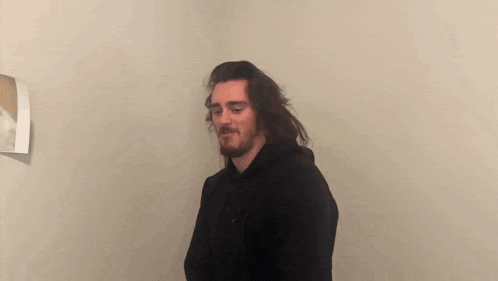 a man with a beard wearing a black hoodie is making a funny face .