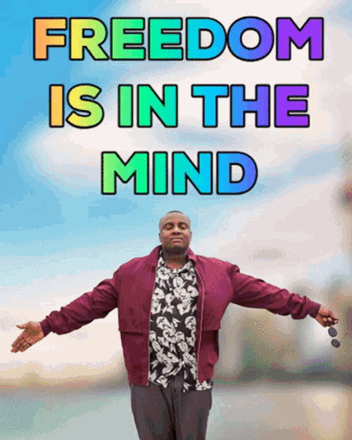 a man with his arms outstretched is standing in front of a sign that says freedom is in the mind