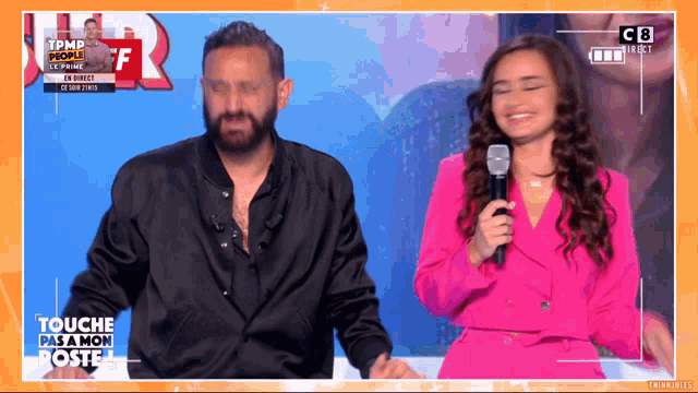 a woman in a pink suit is holding a microphone in front of a man in a black shirt