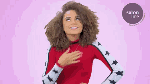 a woman with curly hair is wearing a red sweater with stars on the sleeves