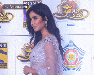 a woman in a white dress is standing in front of a wall with logos on it .