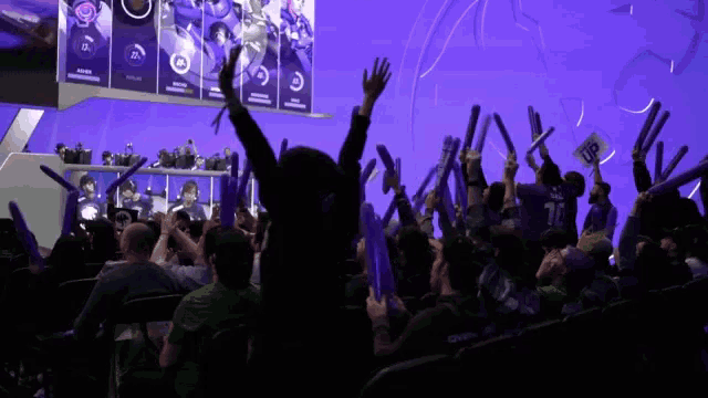 a crowd of people are cheering with their arms in the air and one of them has the number 77 on their back