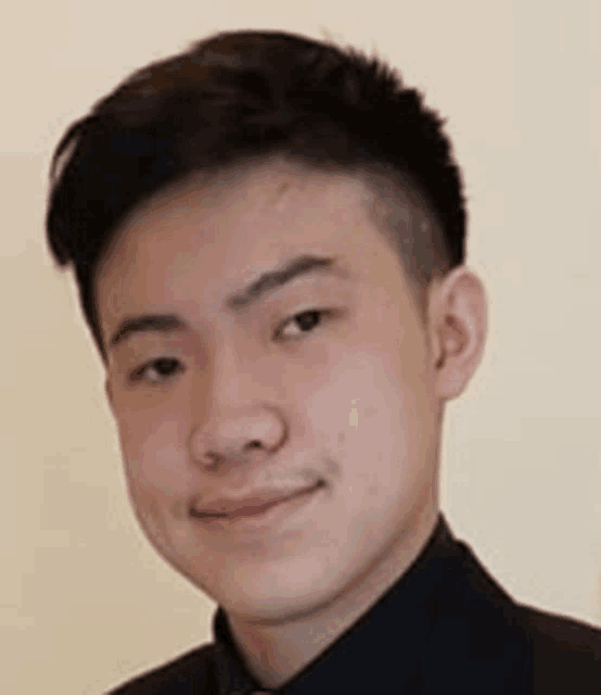 a young man is wearing a suit and tie and smiling for the camera .