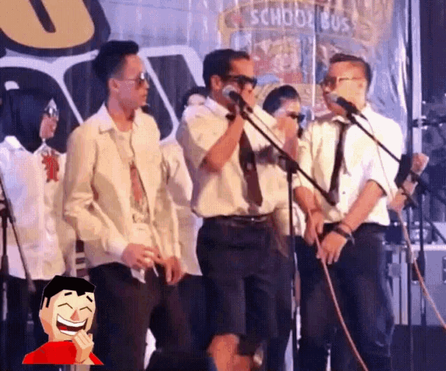a group of men are singing into microphones in front of a school bus banner