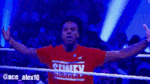 a man in a red shirt with the word shady on it stands in a wrestling ring
