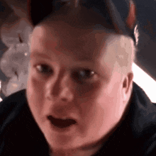 a close up of a person 's face with a shocked look on his face .